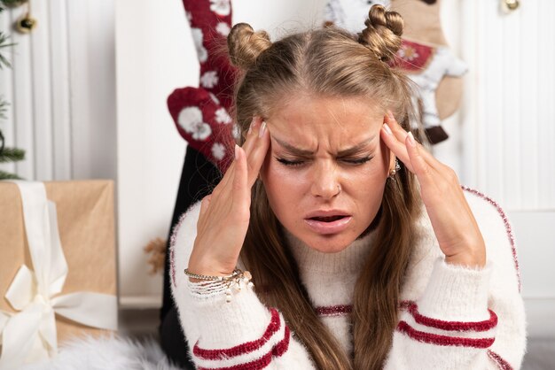 Kostenloses Foto eine junge frau posiert auf teppich im weihnachtsinnenraum liegend.