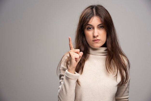 Eine junge Frau posiert und zeigt den Zeigefinger beiseite.