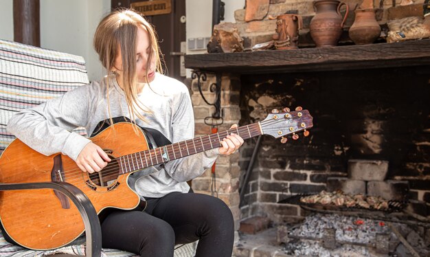 Eine junge Frau spielt in gemütlicher Atmosphäre Gitarre.