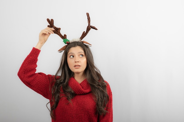 Eine junge Frau steht mit einem Stirnband in Form von Weihnachtshörnern.