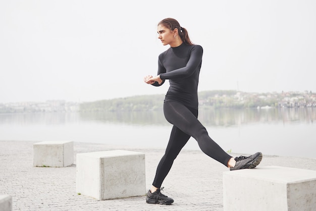 Eine junge Frau treibt am Ufer eines Sees im Park Sport