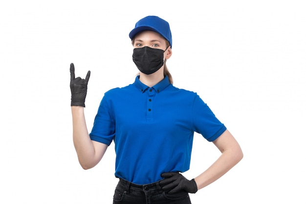 Eine junge Kurierin der Vorderansicht in den schwarzen schwarzen Handschuhen der blauen Uniform und der schwarzen Maske, die mit ihren Händen aufwirft