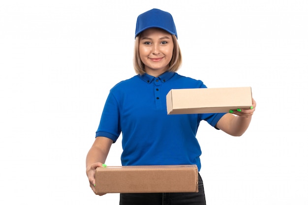 Eine junge Kurierin der Vorderansicht in der blauen Uniform, die Lebensmittellieferungspakete hält