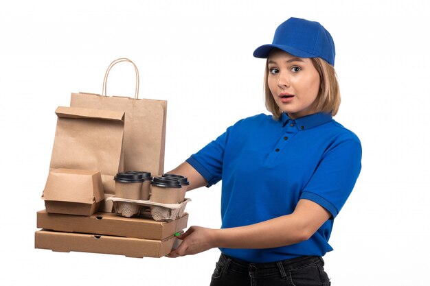 Eine junge Kurierin der Vorderansicht in der blauen Uniform, die Lebensmittellieferungspakete hält