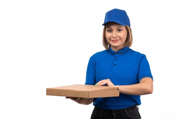 Eine junge Kurierin der Vorderansicht in der blauen Uniform, die Lebensmittellieferungspakete hält