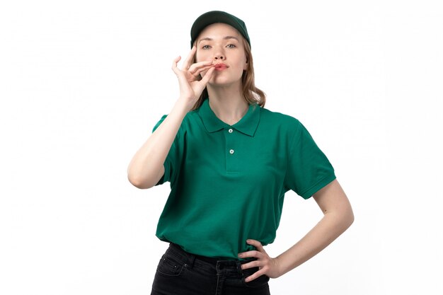 Eine junge Kurierin der Vorderansicht in der grünen Uniform, die mit den Fingern um ihre Lippen aufwirft