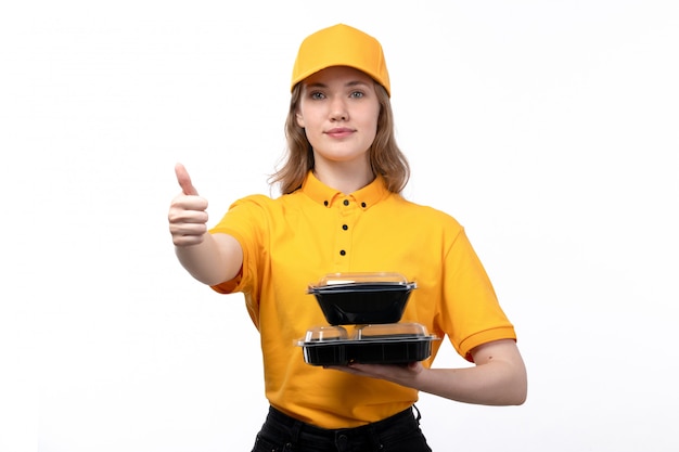 Eine junge Kurierin der Vorderansicht weiblicher Arbeiter des Lebensmittel-Lieferservices lächelnd, das Schüsseln mit Essen auf Weiß hält
