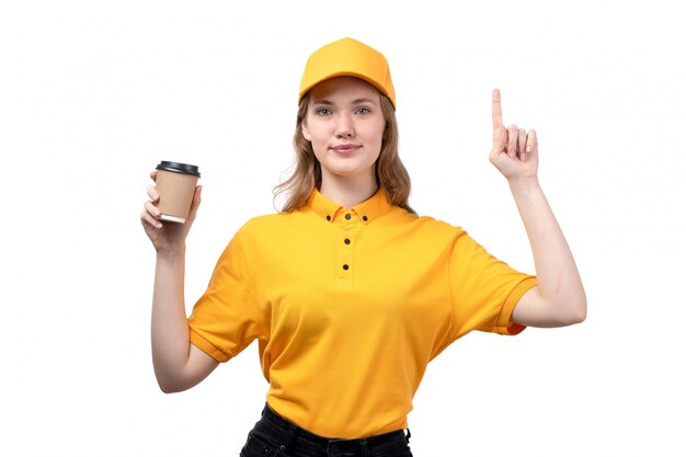 Eine junge Kurierin der Vorderansicht weiblicher Arbeiter des Lebensmittellieferservice lächelnd, der eine Kaffeetasse mit erhöhtem Finger auf Weiß hält