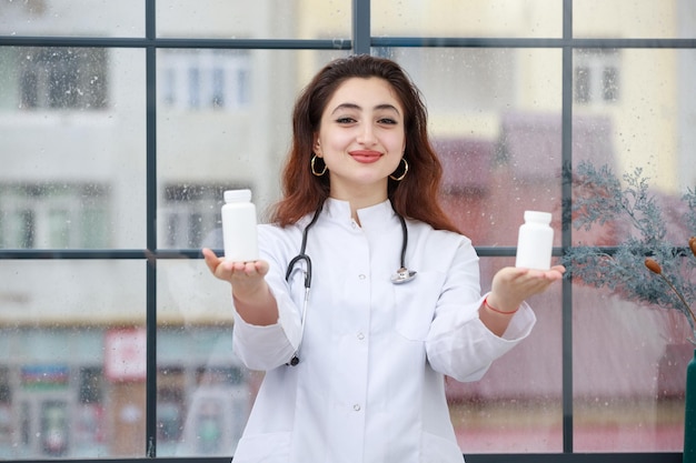 Eine junge Mitarbeiterin des Gesundheitswesens, die mit beiden Händen eine Medikamentenkapsel hält