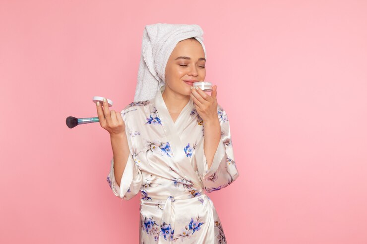 Kostenlose Foto eine junge schöne dame der vorderansicht im bademantel, die bürste und creme hält