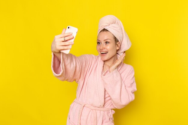 Eine junge schöne Frau der Vorderansicht im rosa Bademantel, der ein Foto macht