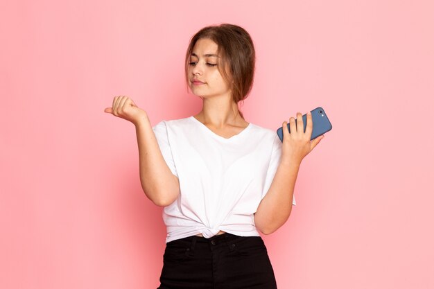 Eine junge schöne Frau der Vorderansicht im weißen Hemd, das ein Telefon hält