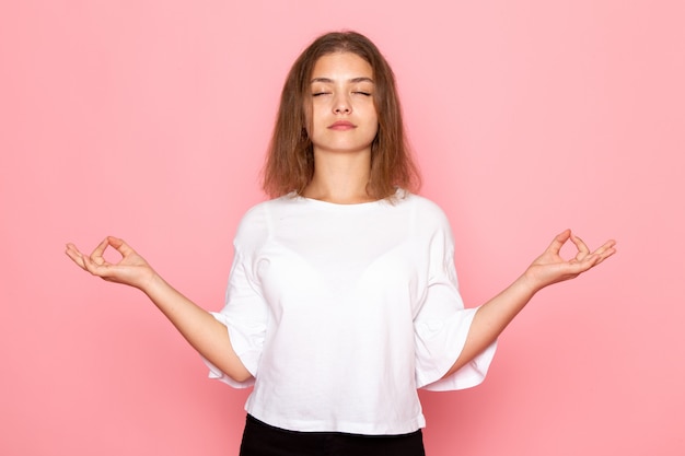 Eine junge schöne Frau der Vorderansicht im weißen Hemd in der Meditationshaltung