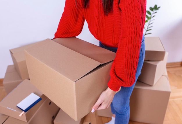 Eine junge schöne Frau macht ihre Notizen und Pläne in ihrer neuen Wohnung Junge Frau Verpackung Karton Umzugskonzept