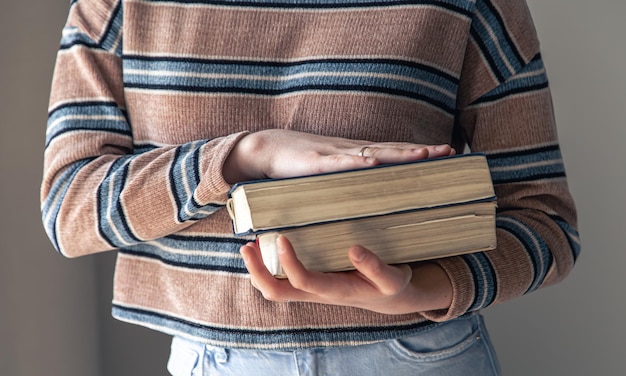 Eine junge Studentin mit Büchern in ihren Händen im Raum