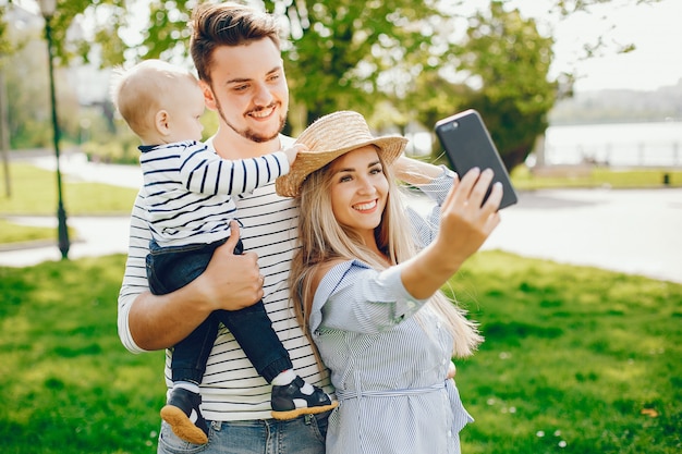 Eine junge und schöne blonde Mutter in einem blauen Kleid, zusammen mit ihrem gutaussehenden Mann