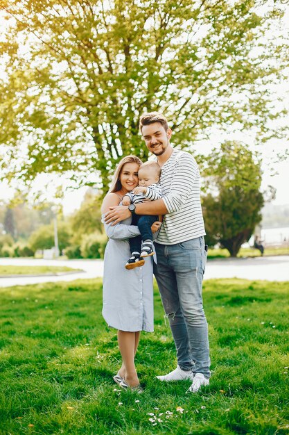 Eine junge und schöne blonde Mutter in einem blauen Kleid, zusammen mit ihrem gutaussehenden Mann