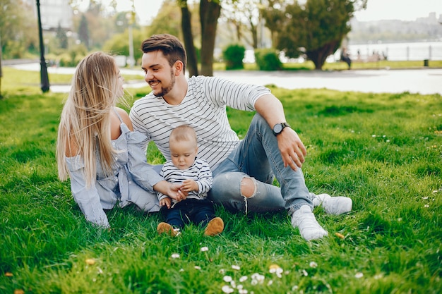 Eine junge und schöne blonde Mutter in einem blauen Kleid, zusammen mit ihrem gutaussehenden Mann