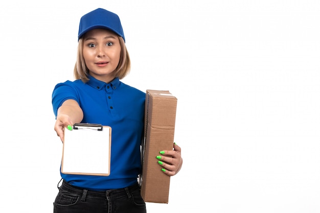 Eine junge weibliche Kurierin der Vorderansicht in der blauen Uniform, die Lebensmittel-Lieferpaket und Notizblock für Unterschriften hält