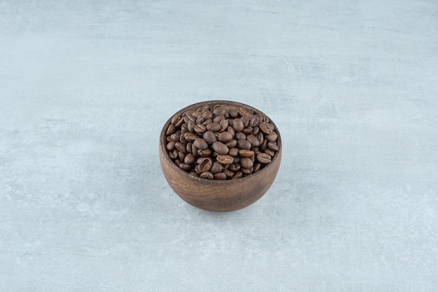 Eine kleine Holzschale mit Kaffeebohnen auf weißem Hintergrund. Foto in hoher Qualität