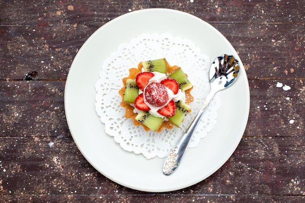 Kostenloses Foto eine kleine köstliche torte der draufsicht mit sahne-innenplatte mit frischen erdbeeren und kiwis auf der dunklen hintergrundplätzchenkekskuchenfrucht