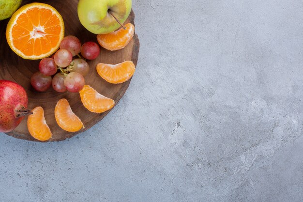 Eine köstliche Portion Früchte auf einem Holzbrett auf Marmorhintergrund.