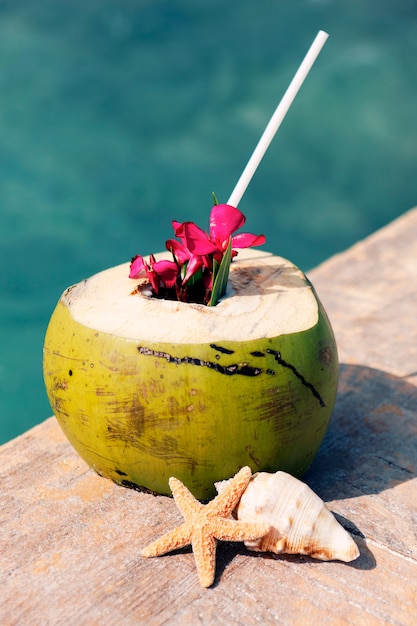 Eine Kokosnuss mit Trinkhalm am Strand im Sommer
