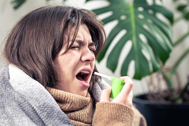 Kostenloses Foto eine kranke junge frau benutzt hustenspray