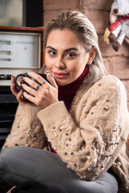 Eine lächelnde Frau, die sitzt und eine Tasse Kaffee hält