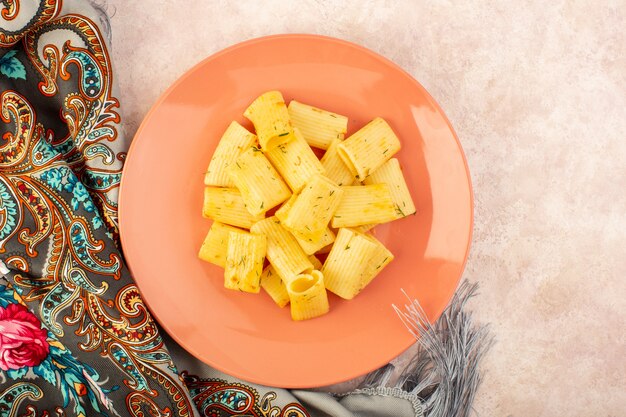 Eine leckere italienische Pasta-Mahlzeit der Draufsicht mit getrockneten grünen Kräutern innerhalb der rosa Platte auf buntem Schal und Rosa