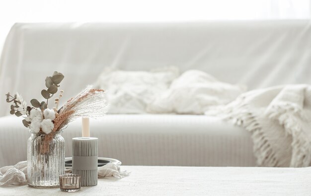 Eine minimalistische Komposition im skandinavischen Stil mit getrockneten Blumen in einer Vase und Kerzen.
