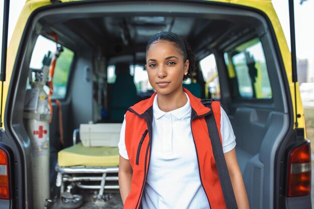 Eine Mitarbeiterin des Krankenwagens kommt mit ihrem Notfallrucksack und ihrem Vitalzeichenmonitor aus dem hinteren Teil eines Krankenwagens