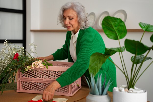 Eine mittelgroße alte Frau kümmert sich um Pflanzen.