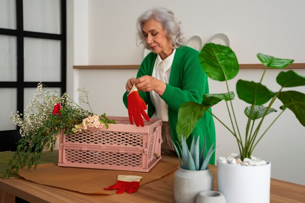 Eine mittelgroße alte Frau kümmert sich um Pflanzen.