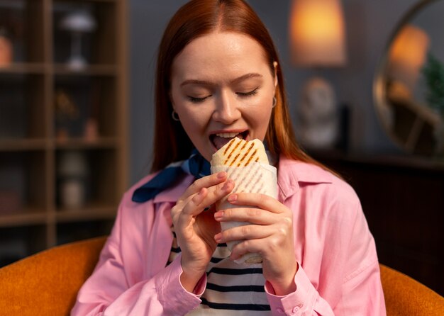 Eine mittelgroße Frau mit einem in Papier gewickelten Sandwich