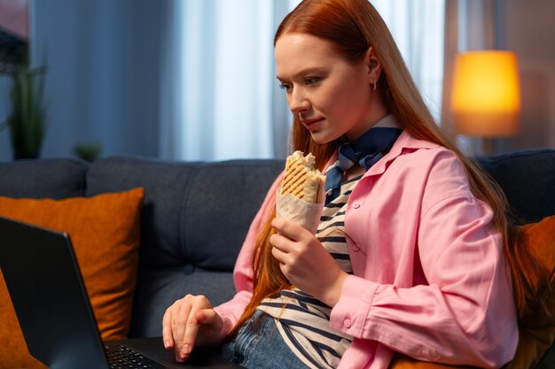 Eine mittelgroße Frau mit einem in Papier gewickelten Sandwich