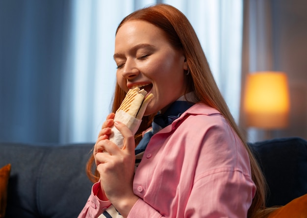 Eine mittelgroße Frau mit einem in Papier gewickelten Sandwich