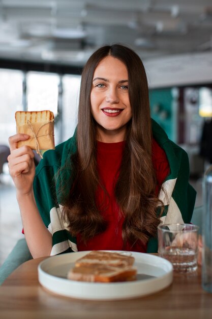 Eine mittelgroße Frau mit einem in Papier gewickelten Sandwich