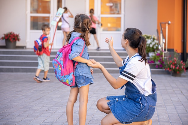 Eine Mutter begleitet den Schüler zur Schule, ein glückliches kleines Mädchen mit einer fürsorglichen Mutter, zurück zur Schule.