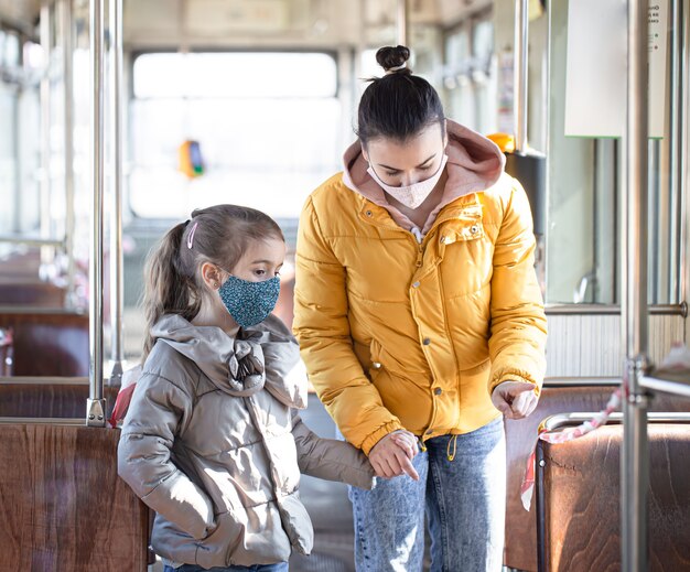 Eine Mutter mit einem Kind in einem leeren öffentlichen Verkehr, die während einer Pandemie Masken trägt. Coronavirus.