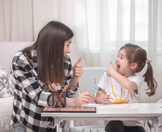 Eine Mutter mit einem Kind sitzt am Tisch und macht Hausaufgaben. Das Kind lernt zu Hause. Heimunterricht. Platz für Text.