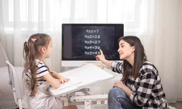 Eine Mutter mit einem Kind sitzt am Tisch und macht Hausaufgaben.