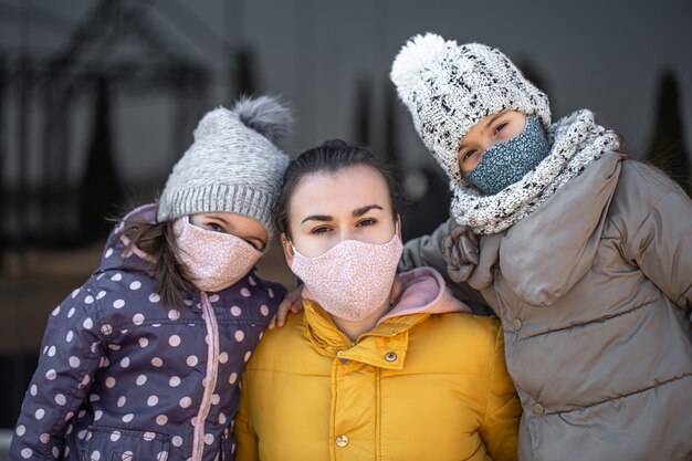 Eine Mutter mit zwei Töchtern in Masken während der Pandemie Coronavirus.