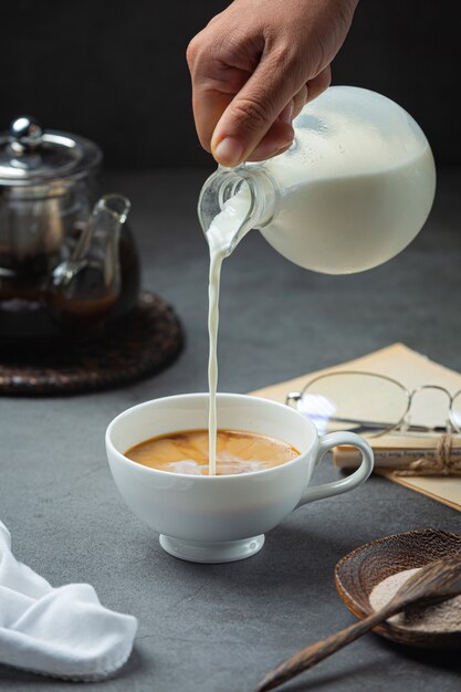 Eine Nahaufnahme einer Hand, die Kaffeewasser in eine Kaffeetasse gießt, internationales Kaffeetagkonzept