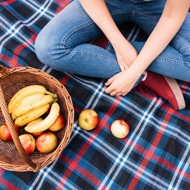 Eine obenliegende Ansicht der Frau sitzend auf Decke mit Obstkorb
