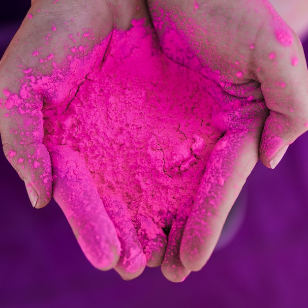 Eine obenliegende Ansicht der Hand des Menschen rosa holi Farbe halten