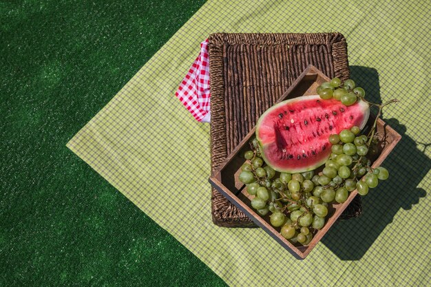 Eine obenliegende Ansicht der Wassermelonen- und Traubenrahmen auf Picknickkorb