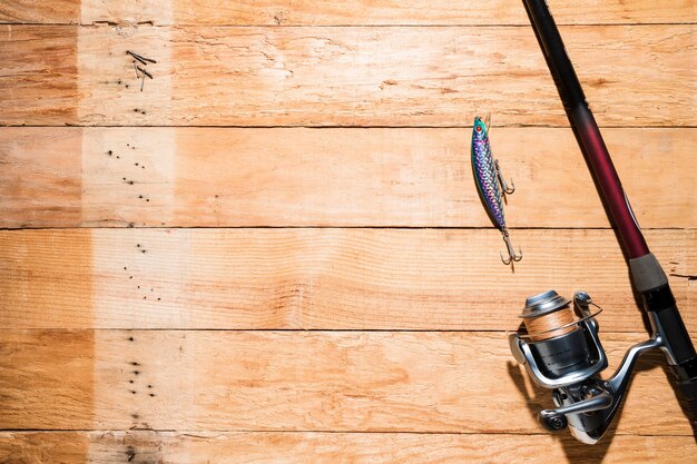 Eine obenliegende Ansicht des Fischköders mit Angelrute auf Schreibtisch