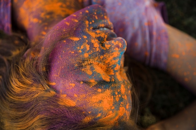 Eine obenliegende Ansicht des orange holi Farbpulvers auf dem Gesicht der Frau