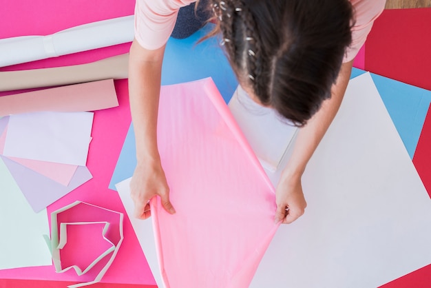 Eine obenliegende Ansicht einer Frau, die rosafarbenes Kartenpapier anhält